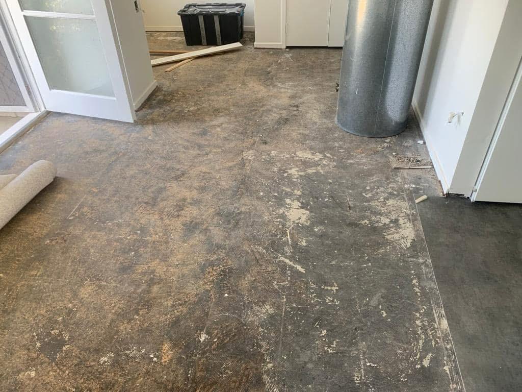 Room stripped back to bare concrete subfloor with the old carpet removed